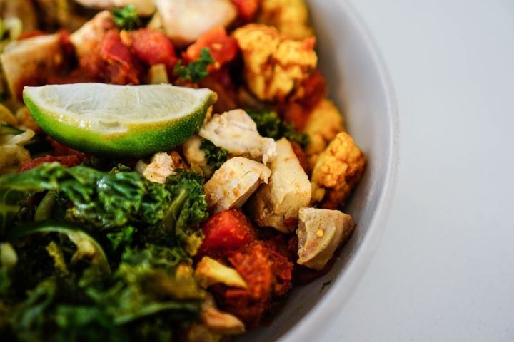 Vibrant salad with chicken, kale, and lime in a bowl, offering a healthy and colorful dish
