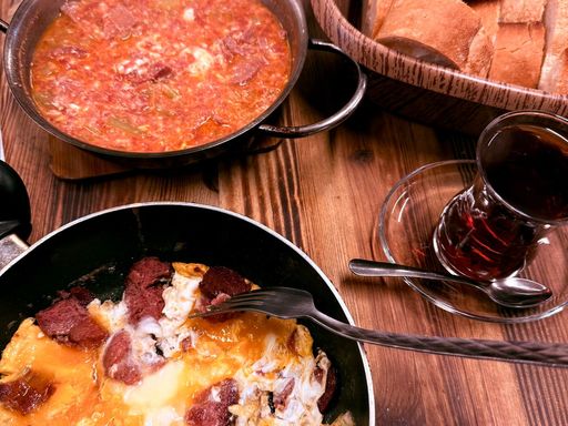Traditional Turkish breakfast featuring menemen, bread, and tea.
