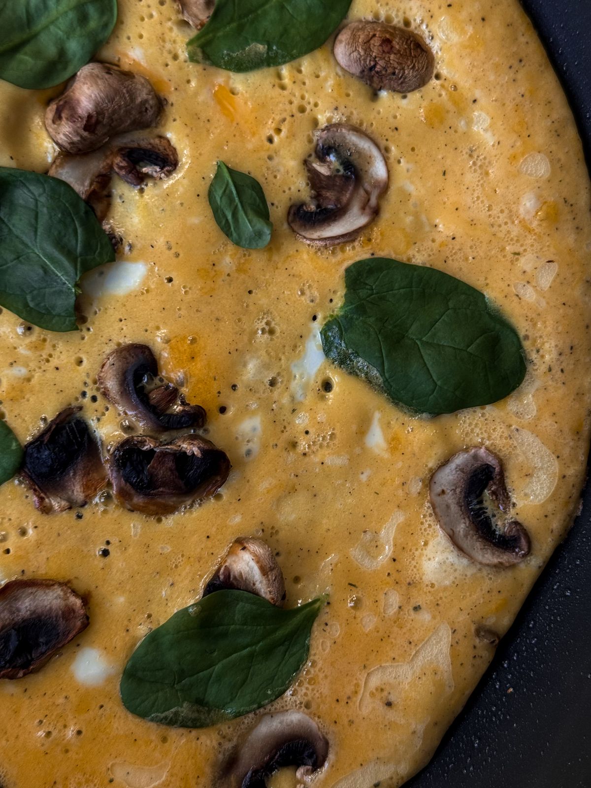 Mushroom and spinach omelette in a frying pan.