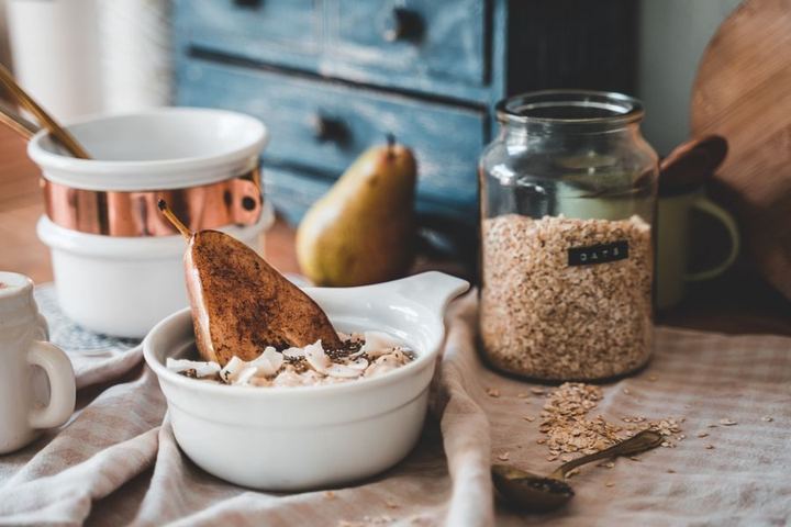 A cozy breakfast scene with a bowl of oats, sliced pear, and a rustic kitchen setting.
