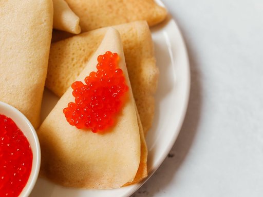 Thin blini pancakes folded with red caviar