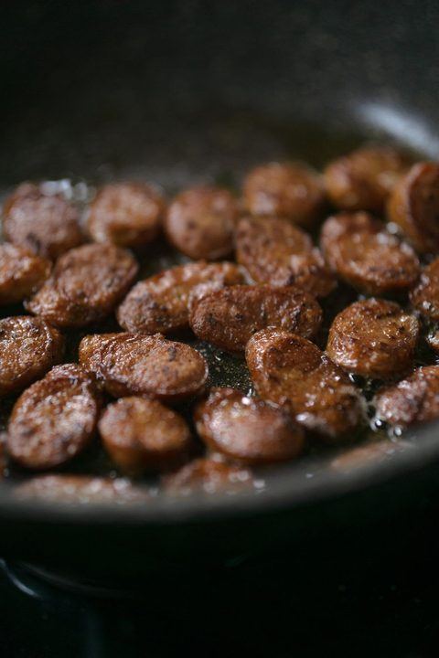 Deliciously browned sausage slices frying in a pan, perfect for culinary or cooking themes