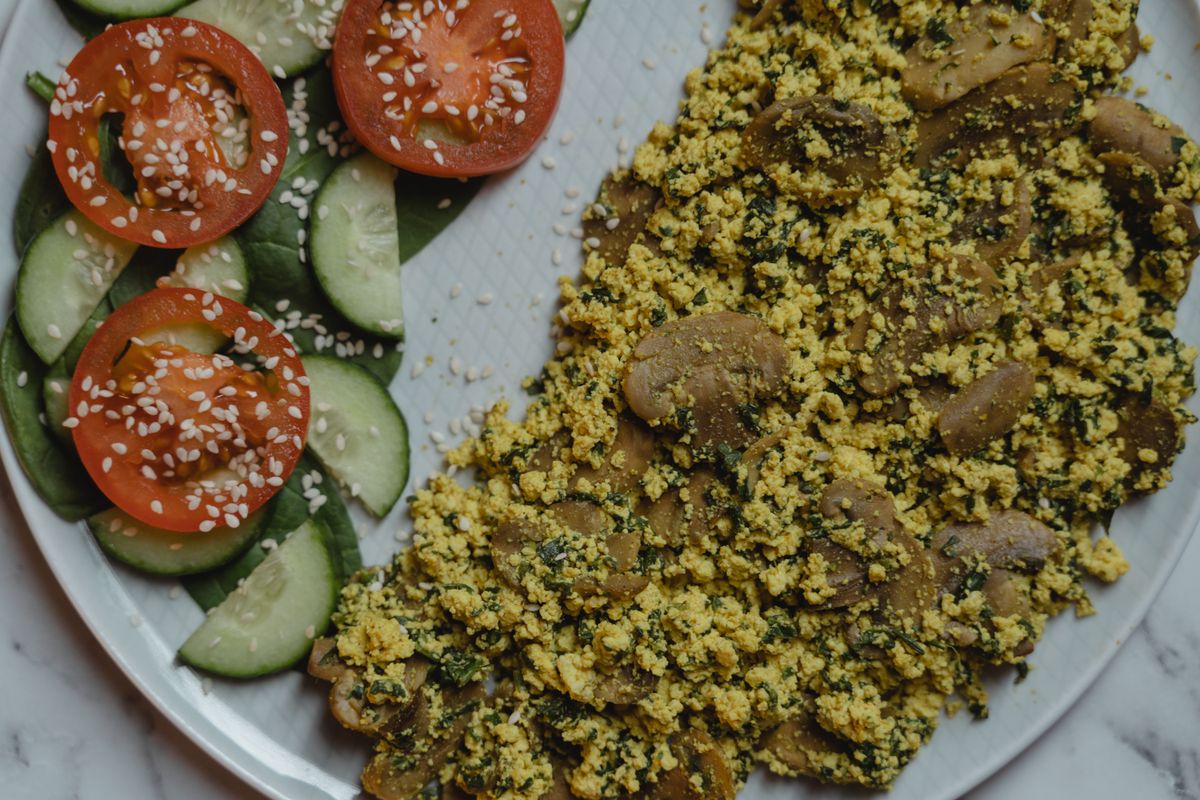 Vegan tofu scramble served with tomatoes and cucumbers.