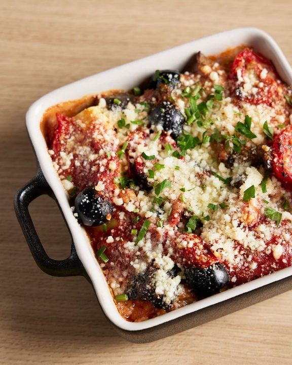 Delicious Italian baked pasta topped with cheese, tomatoes, and olives in a casserole dish