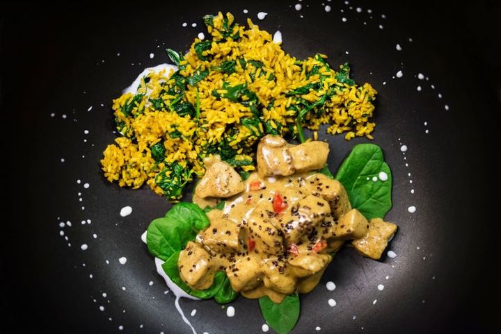 Delicious chicken curry with creamy sauce and spinach-infused rice.