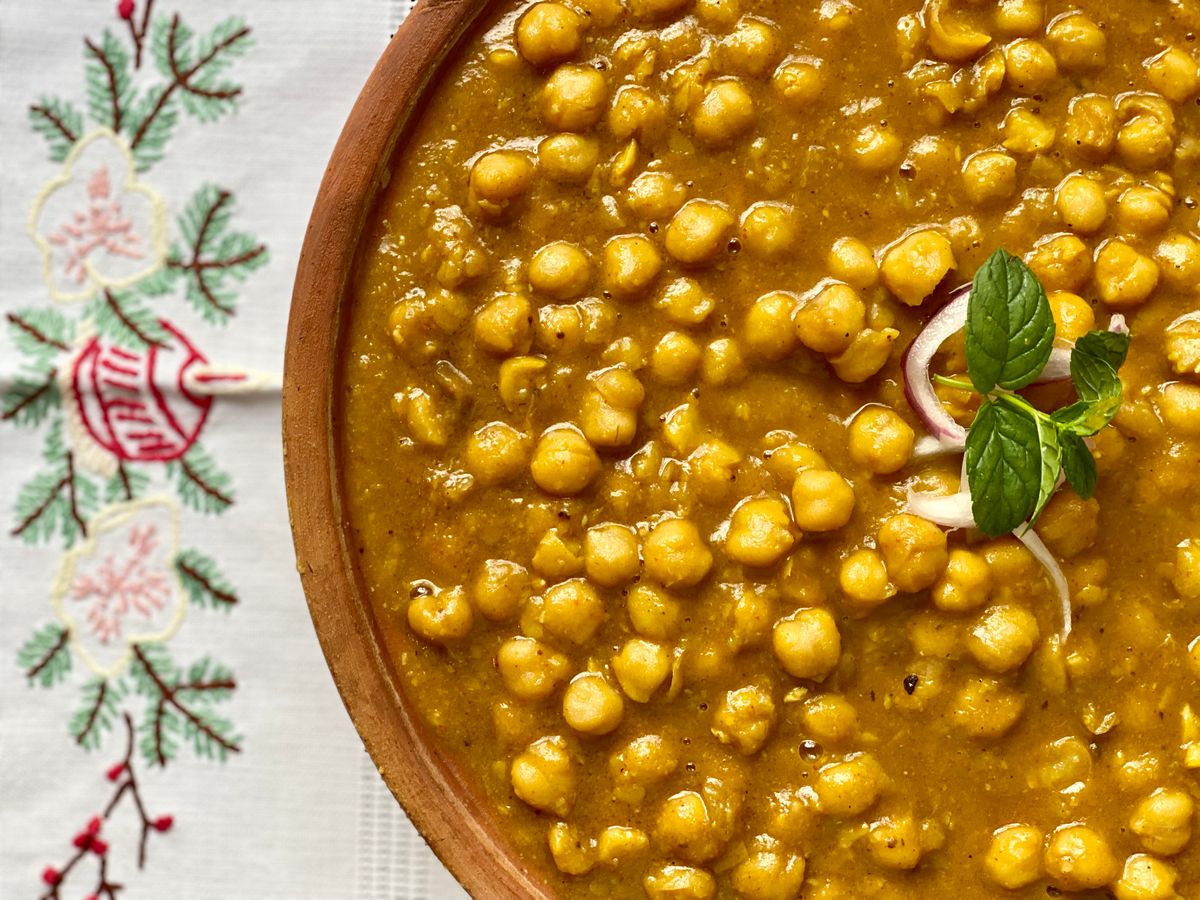 Close-up of chana masala garnished with mint and onion.