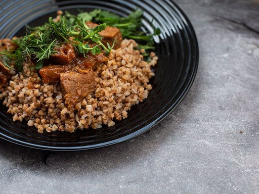 Buckwheat kasha with meat and dill on a dark plate