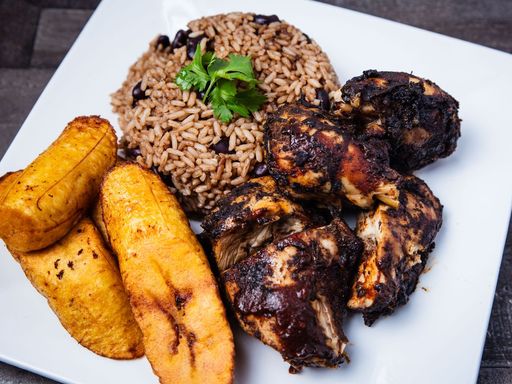 Caribbean jerk chicken served with rice, beans, and fried plantains.
