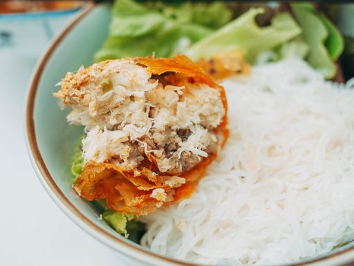 Crispy spring roll on rice vermicelli noodle salad bowl with greens