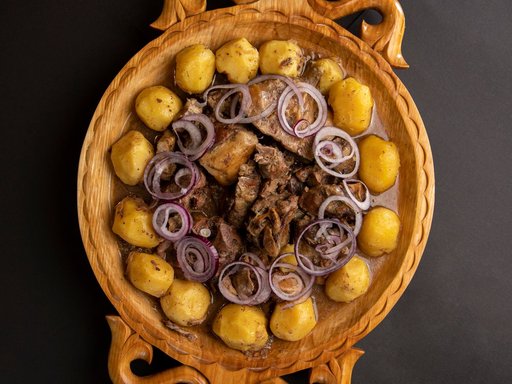Central Asian meat and onion dish on a carved wooden platter