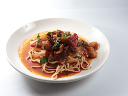 Lagman-style noodles with meat and vegetable sauce in a white bowl