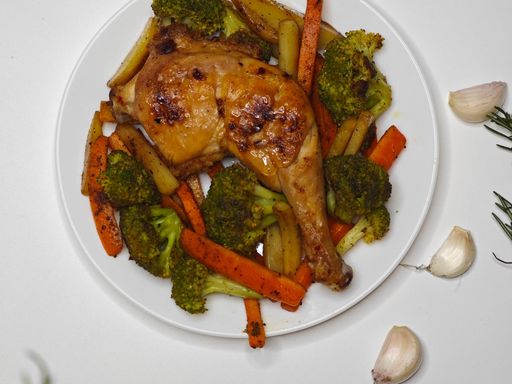 Roasted chicken leg with carrots, broccoli and potatoes on a plate