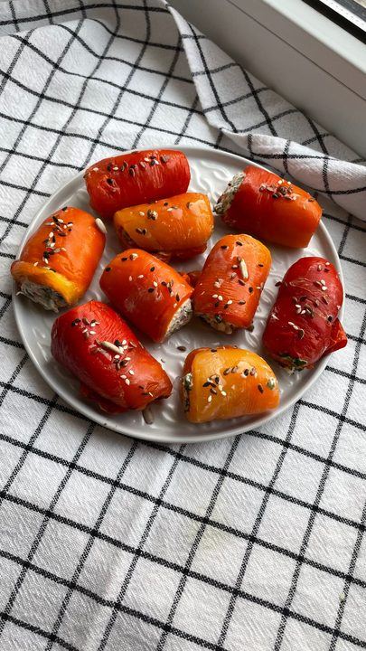 Colorful stuffed bell peppers garnished with seeds on a plate.