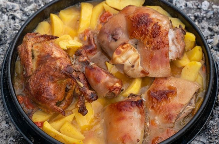 Delicious roasted meat and potatoes served in a rustic pan outdoors.