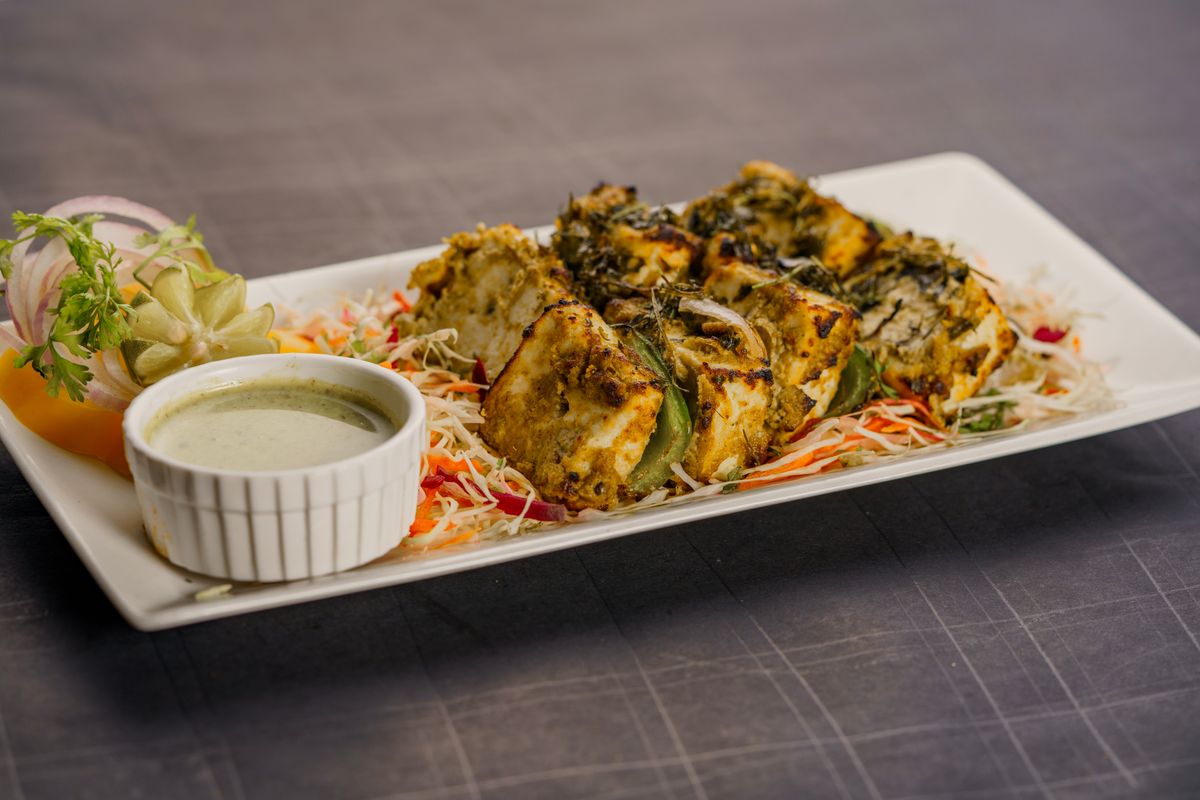 Herb-crusted paneer tikka served with chutney and salad.