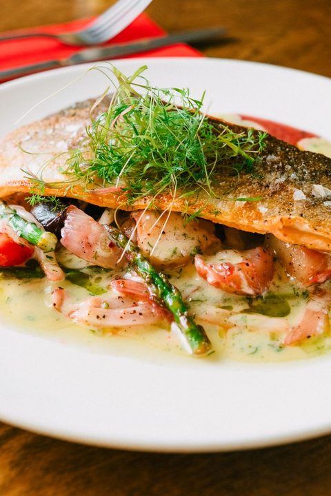 Delicious grilled salmon served with asparagus, shrimp, and dill on a white plate.