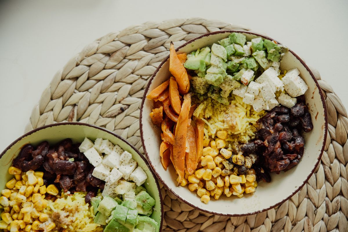 Vegetarian bowls with avocado, corn, beans, and cheese.