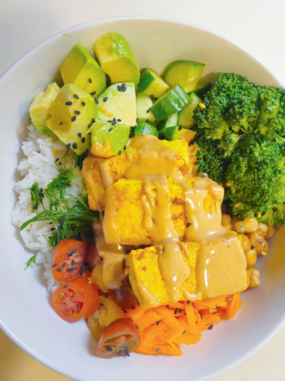 Vegan bowl with tofu, avocado, broccoli, and vegetables.