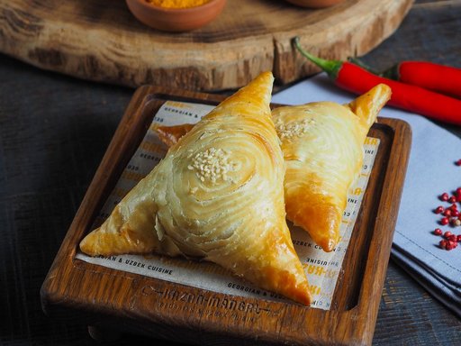 Close-up of baked samsa pastries on a wooden board