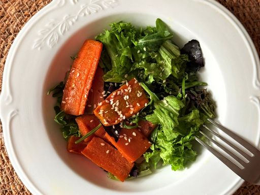 Carrot and lettuce salad with sesame seeds in a white bowl.