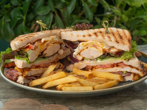 Club sandwich with lettuce and tomato served with fries on a plate