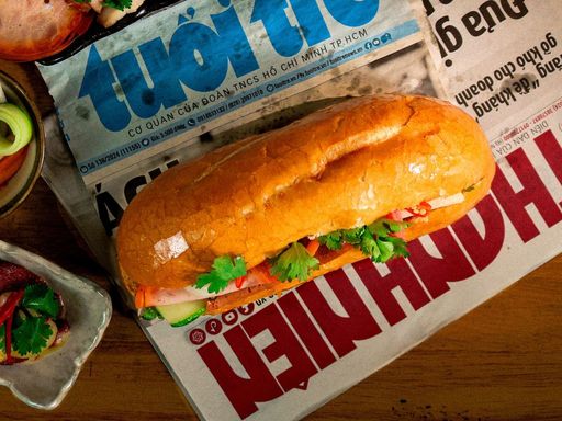 Vietnamese banh mi sandwich with fresh ingredients on newspaper