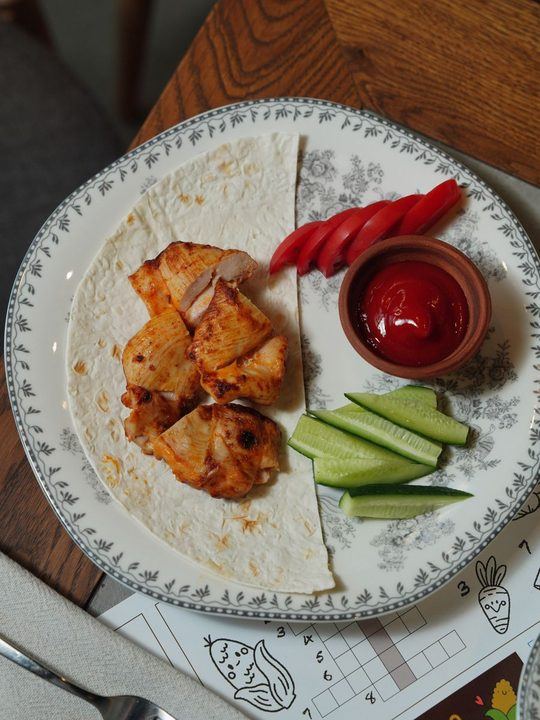 Delicious grilled chicken tortilla wrap with fresh vegetables and ketchup.
