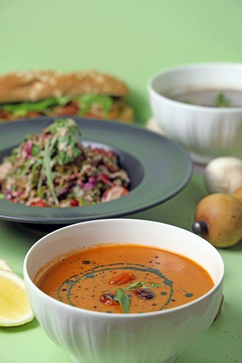 Close-up of a delicious gourmet soup and salad meal with fresh herbs and spices on a green background.