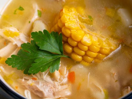 Chicken soup with corn, carrot, and parsley.