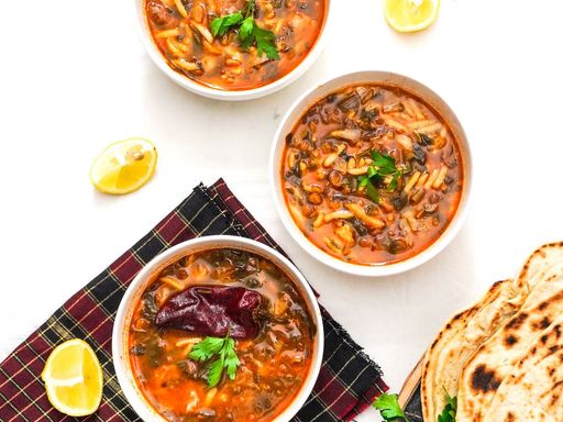 Moroccan harira soup bowls with herbs, lemon, and flatbread.