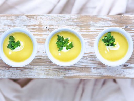 Three bowls of leek and potato soup garnished with fresh parsley.