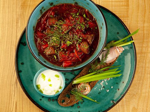 Top view of traditional borscht served with garnish and cream on a rustic wooden table