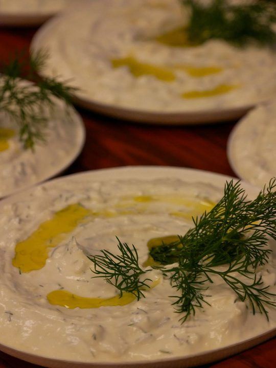 Close-up of delicious creamy tzatziki dip garnished with dill and drizzled with olive oil 