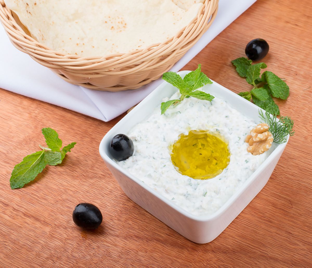 Creamy tzatziki dip with olive oil, herbs, and bread.