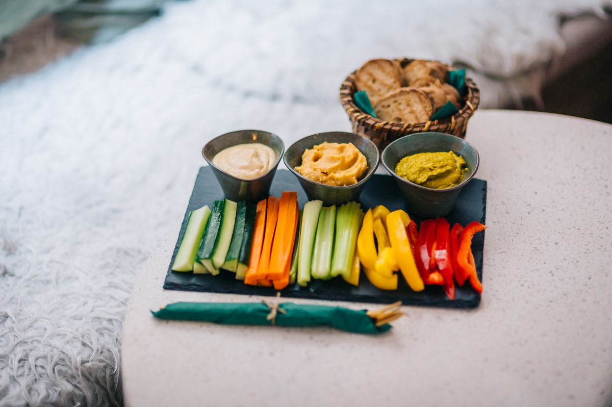 Colorful vegetable platter with dips and bread.