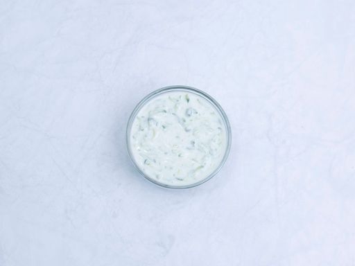 Creamy tzatziki sauce in a glass bowl.