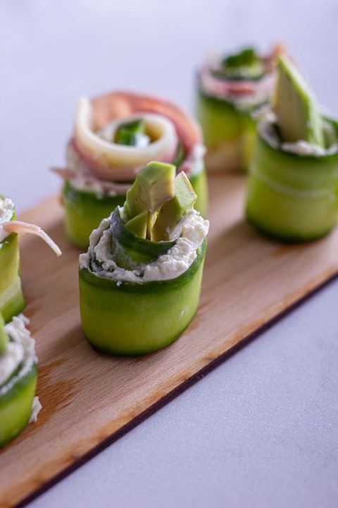 Fresh cucumber rolls with avocado and cream cheese on a wooden board.