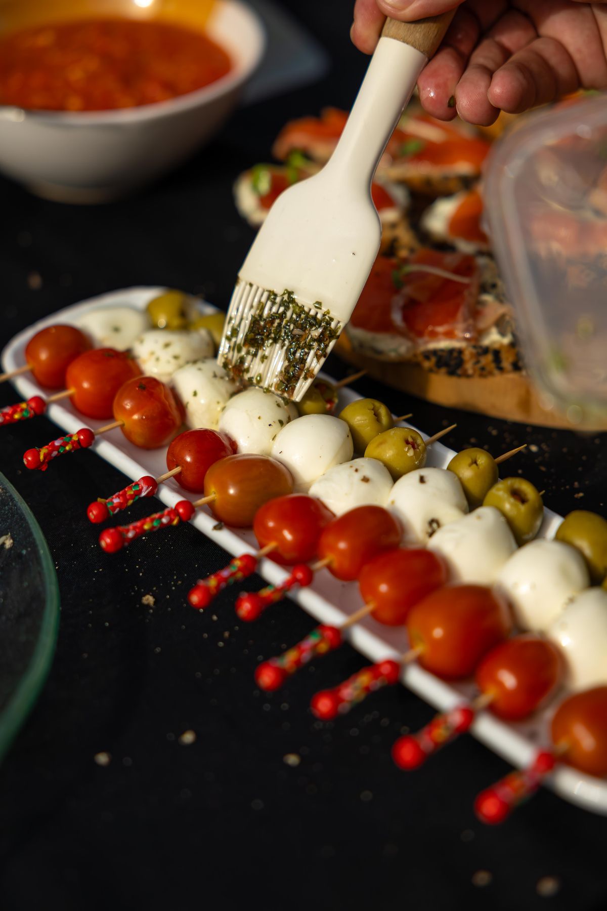 Caprese skewers with cherry tomatoes, mozzarella, olives, and herbs.
