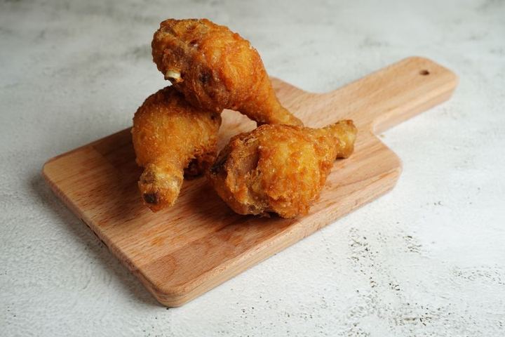 Golden fried chicken drumsticks placed on a wooden cutting board, perfect for a hearty meal.